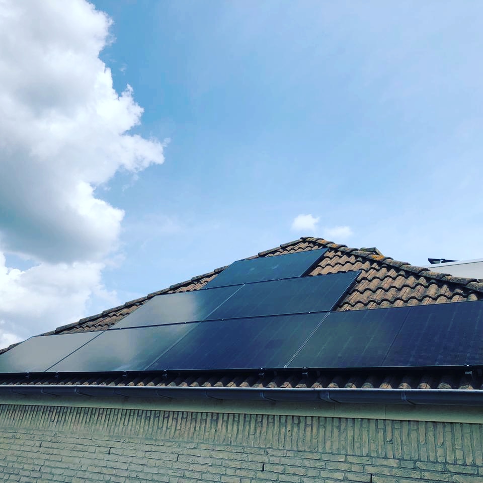 Twaalf zwarte zonnepanelen op een schuin pannendak