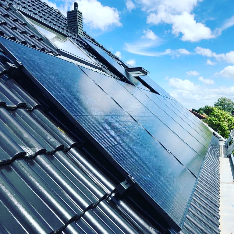 Zonnepanelen rond een dakkapel op een dak met rode pannen
