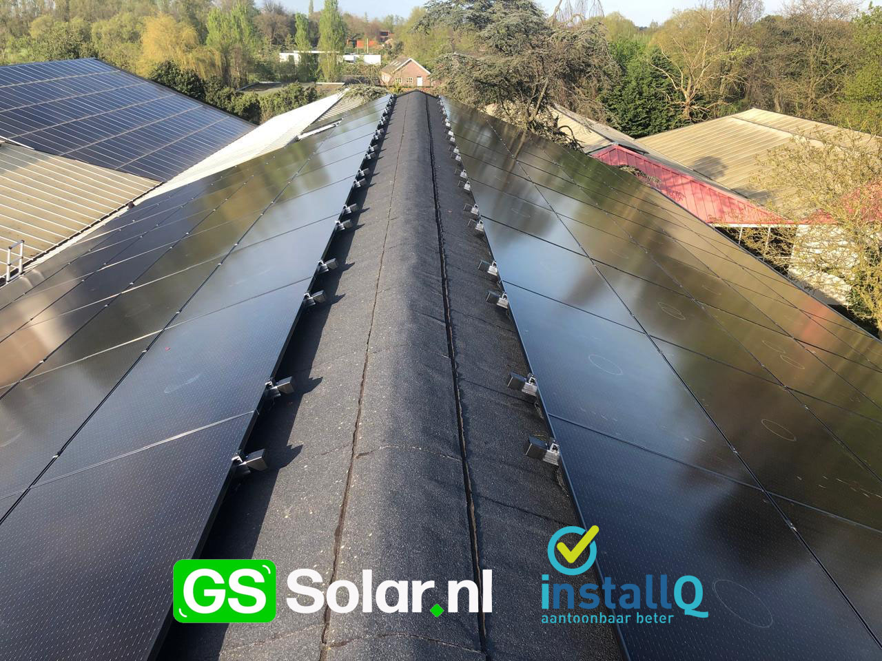 Zonnepanelen op het schuine bitumen dak van een school, zonder ballast