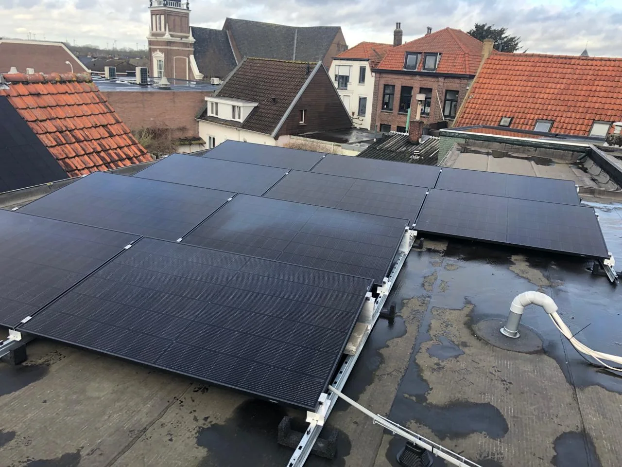 Compact zonnepaneelveld van GS Solar op een plat dak tussen bestaande bebouwing