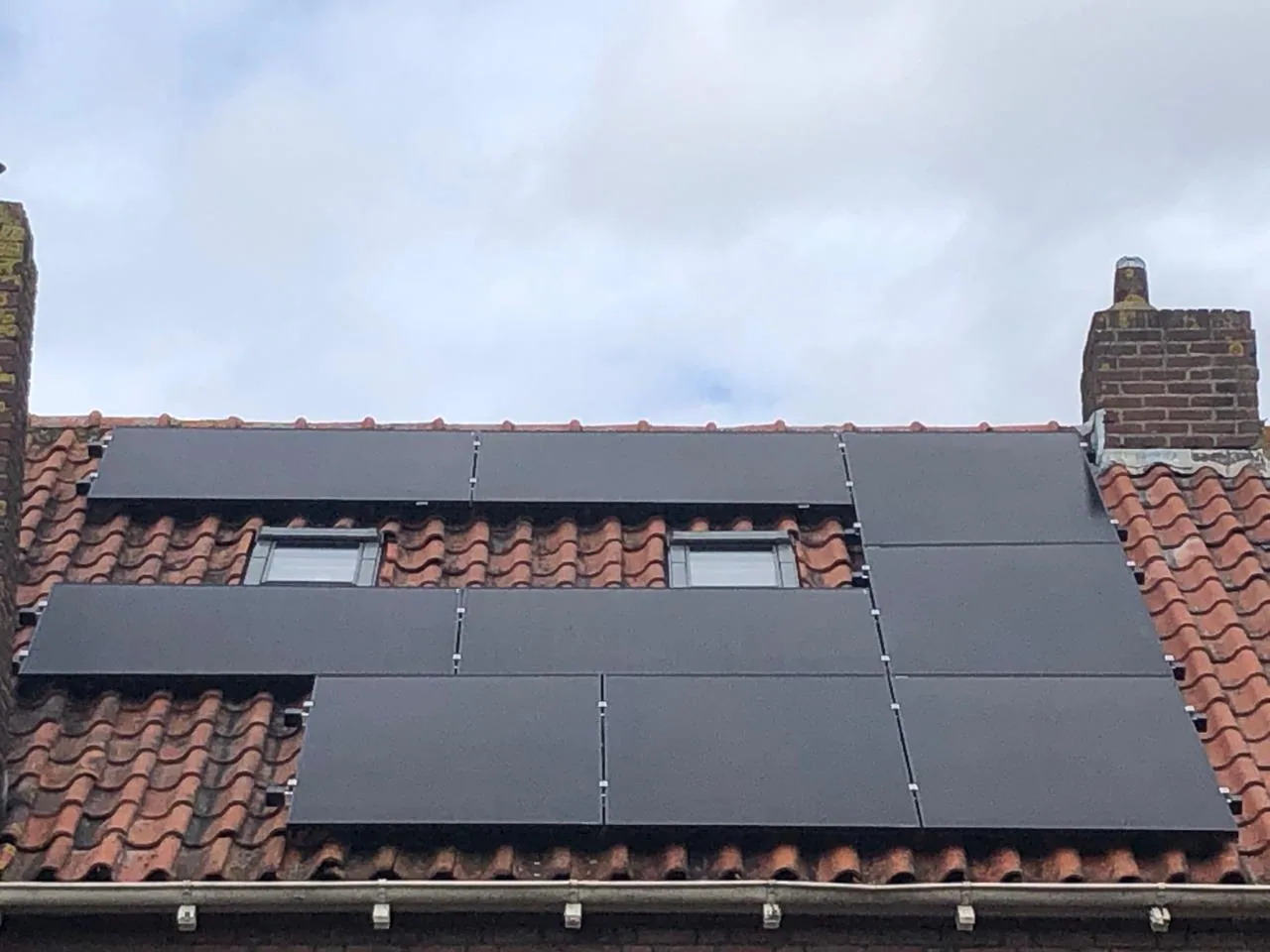 Full-black zonnepanelen op een rood pannendak rond meerdere dakramen