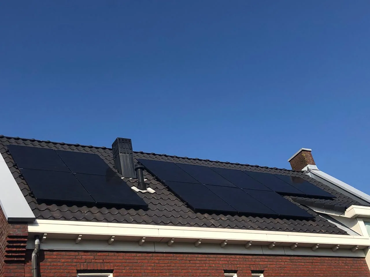 Full-black zonnepanelen op een donker pannendak van een woonhuis